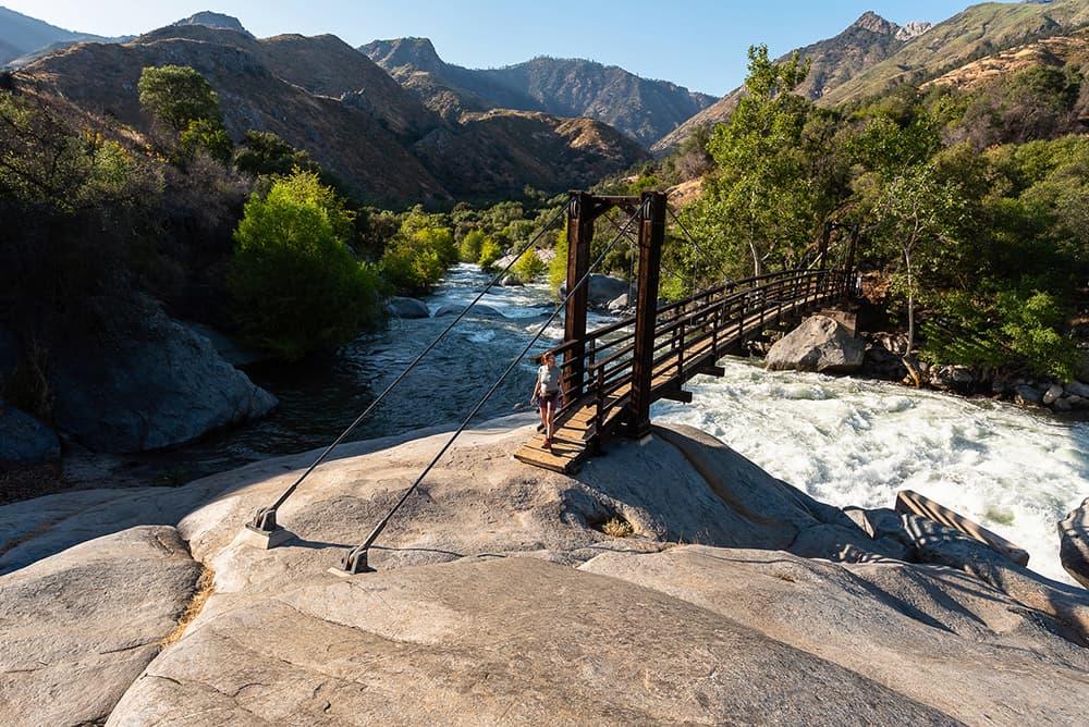 woman crossing bridge over river